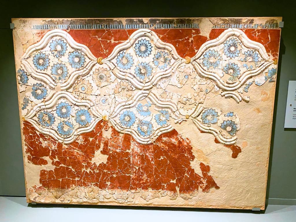 Santorini, Greece Travel Guide: Essential Tips for First-Time Visitors 17 Fresco of decorative rosette patterns displayed at the Museum of Prehistoric Thera in Santorini, Greece, featuring repeating circular floral motifs painted in red and blue tones on a light background.