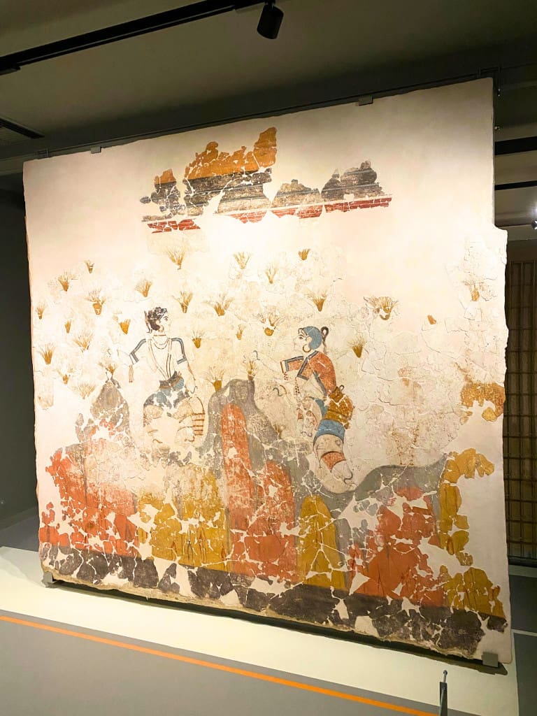 Santorini, Greece Travel Guide: Essential Tips for First-Time Visitors 14 “Saffron Gatherers” fresco housed in the Museum of Prehistoric Thera in Santorini Greece depicting stylized female figures harvesting saffron flowers with vibrant colors and flowing forms.