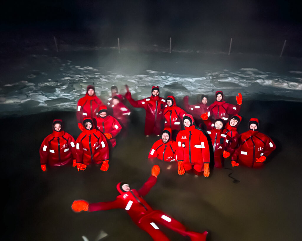 Guide to Spotting the Aurora Borealis in Rovaniemi, Finland 5 Group of people enjoying winter activities in red Ice Floating suits in Lapland.